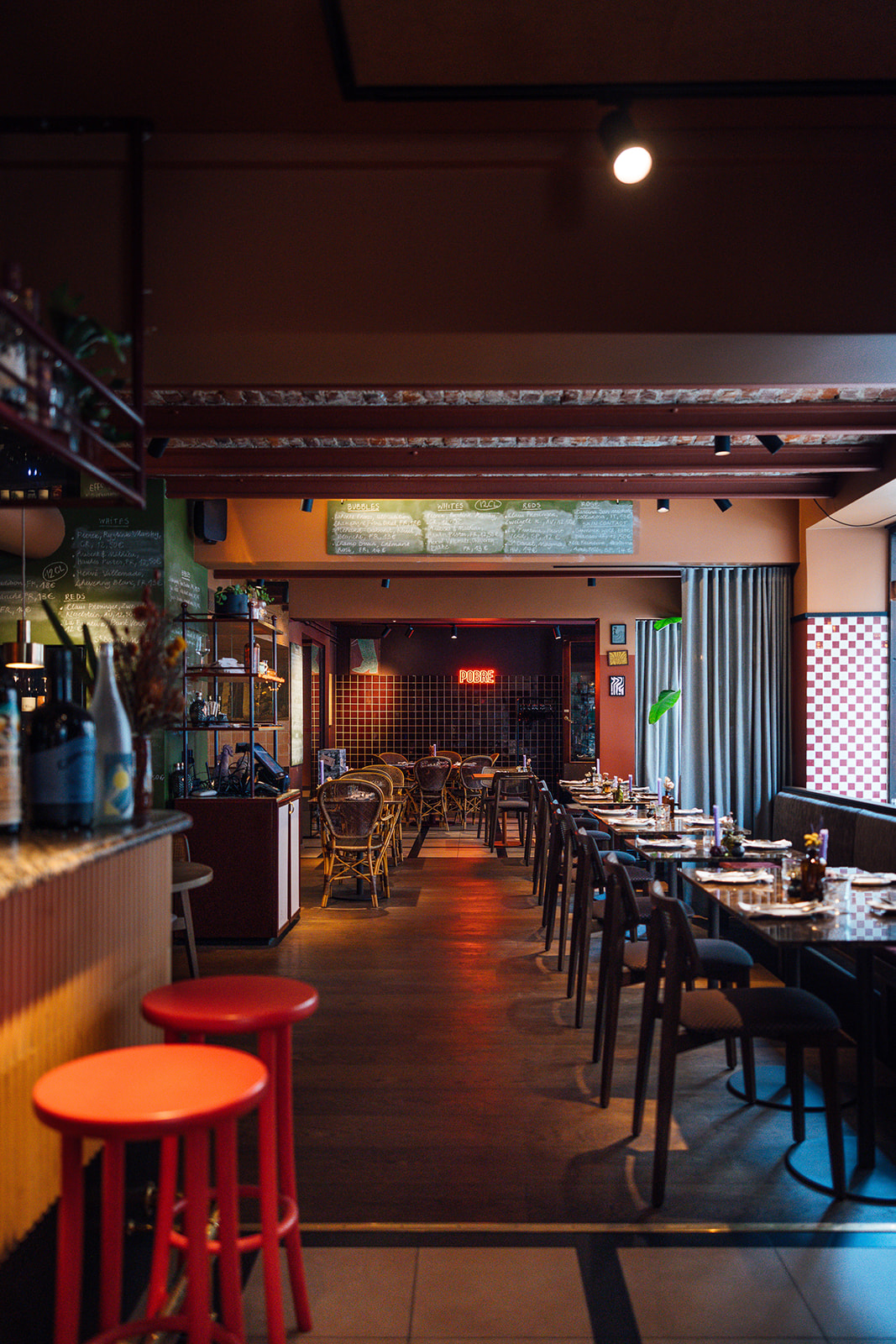 Pobre's dining room mid-service — warm light, full tables, plates landing in the middle.